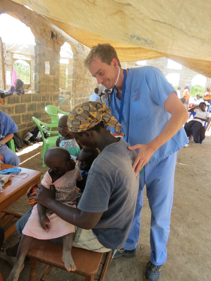 Doctor listening to african man's heart beat in outdoor clinic